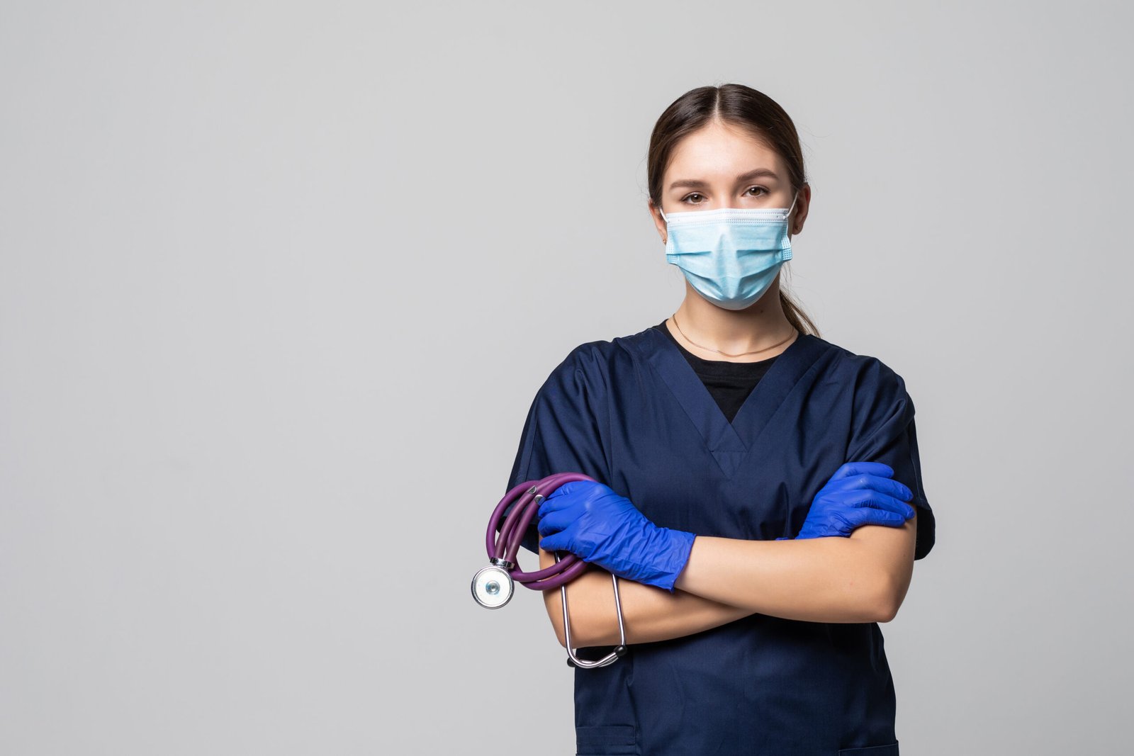 Portrait of young female doctor in medical mask looking at camera isolated on white